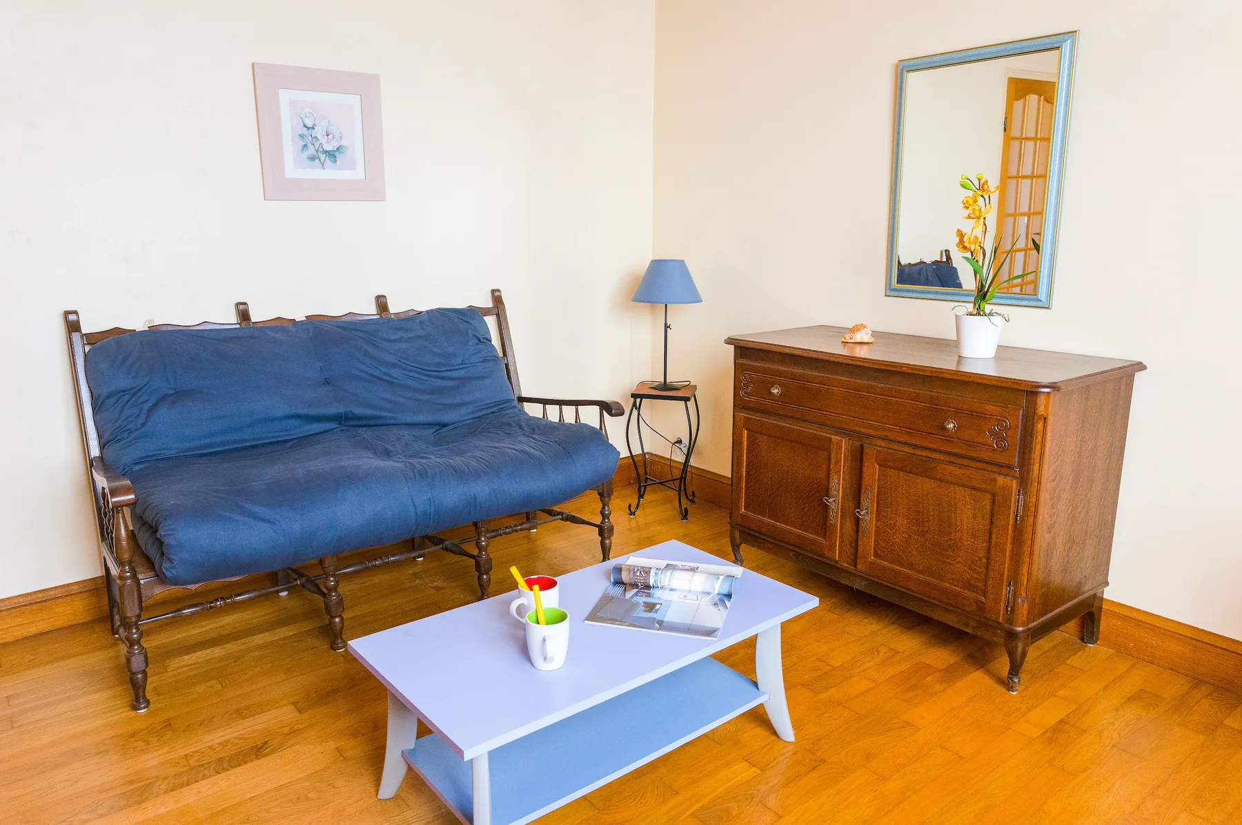A furnished sitting area with blue seating and a wooden cabinet.