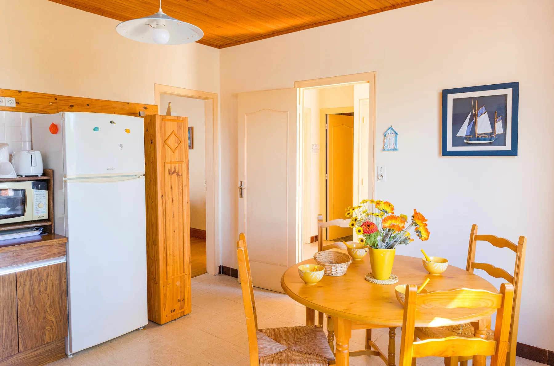 A dining area with a wooden table and colorful flowers.