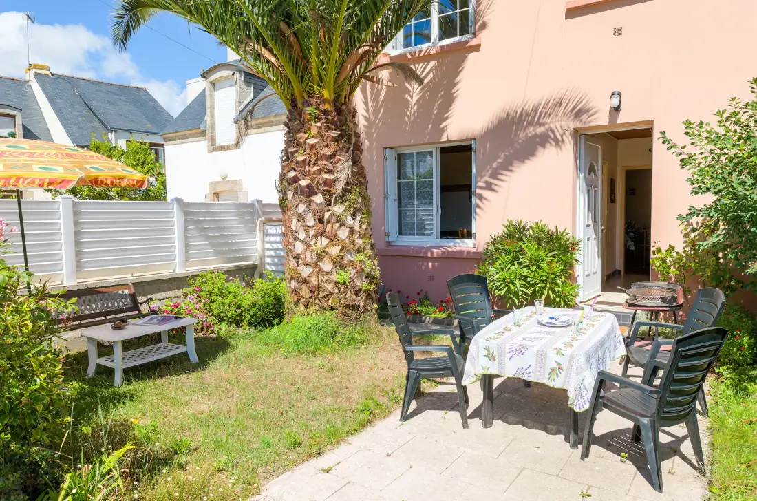 A garden patio with outdoor seating beside a peach-colored house.