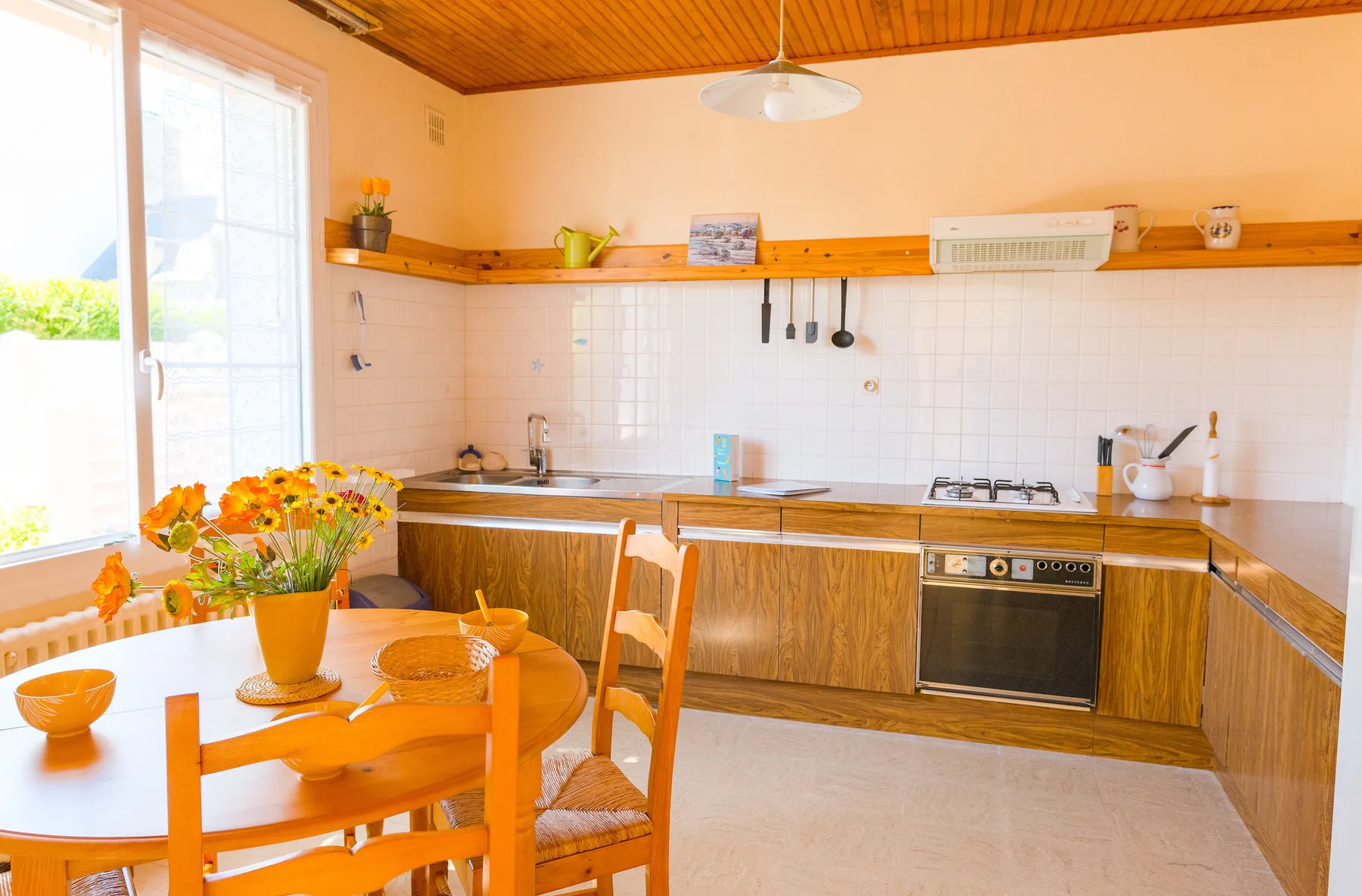 A bright kitchen with a wooden dining table beside the windows.
