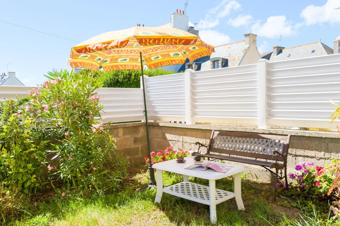 A garden seating area with a table, bench, and colorful umbrella.