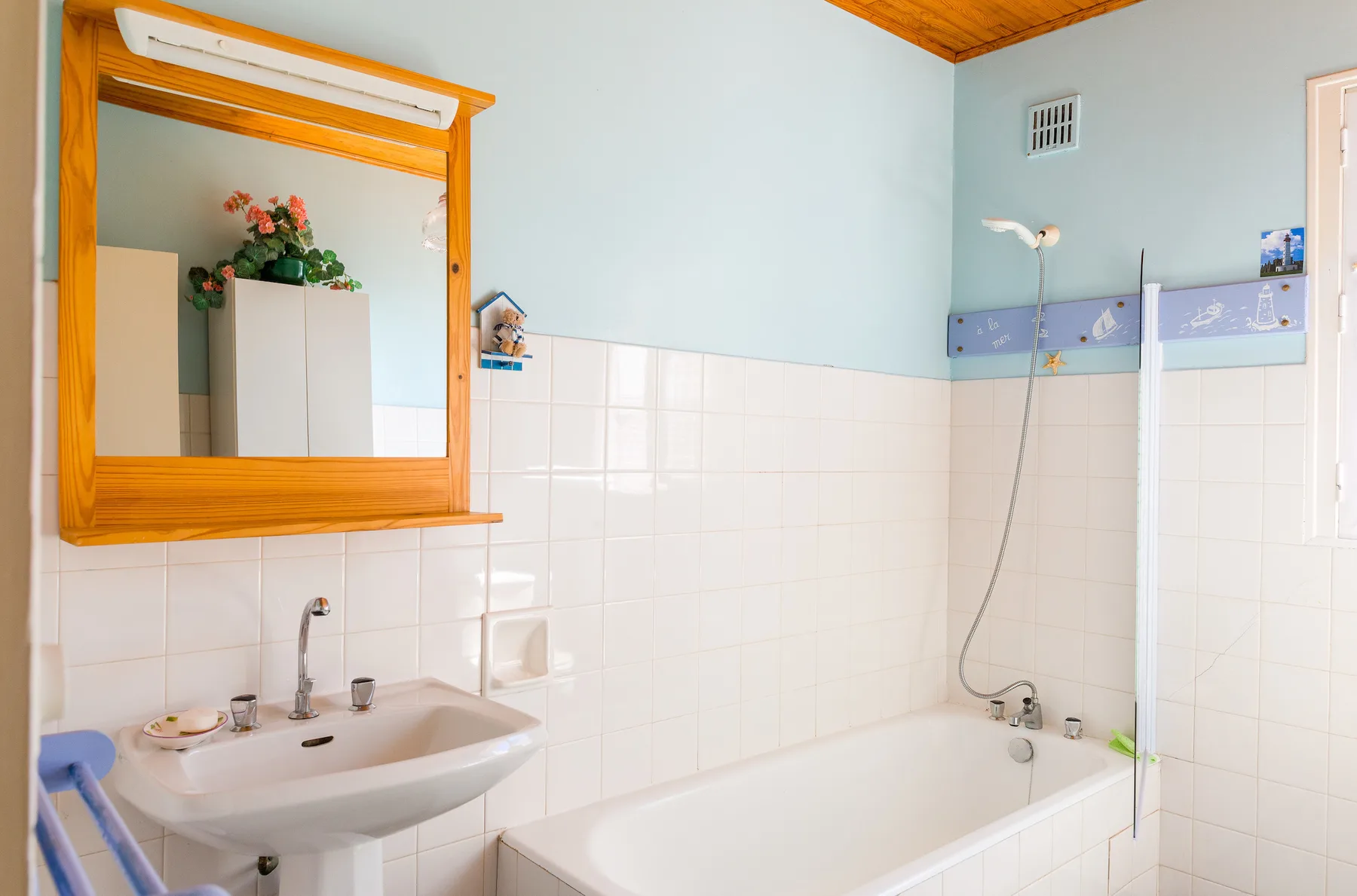 A tiled bathroom with a bathtub, sink, and large framed mirror.