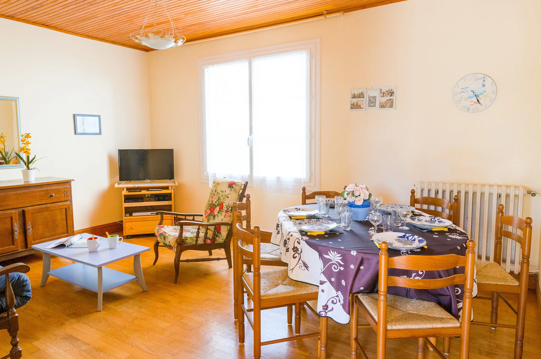 A dining room with a table set near a bright window and a seating area.