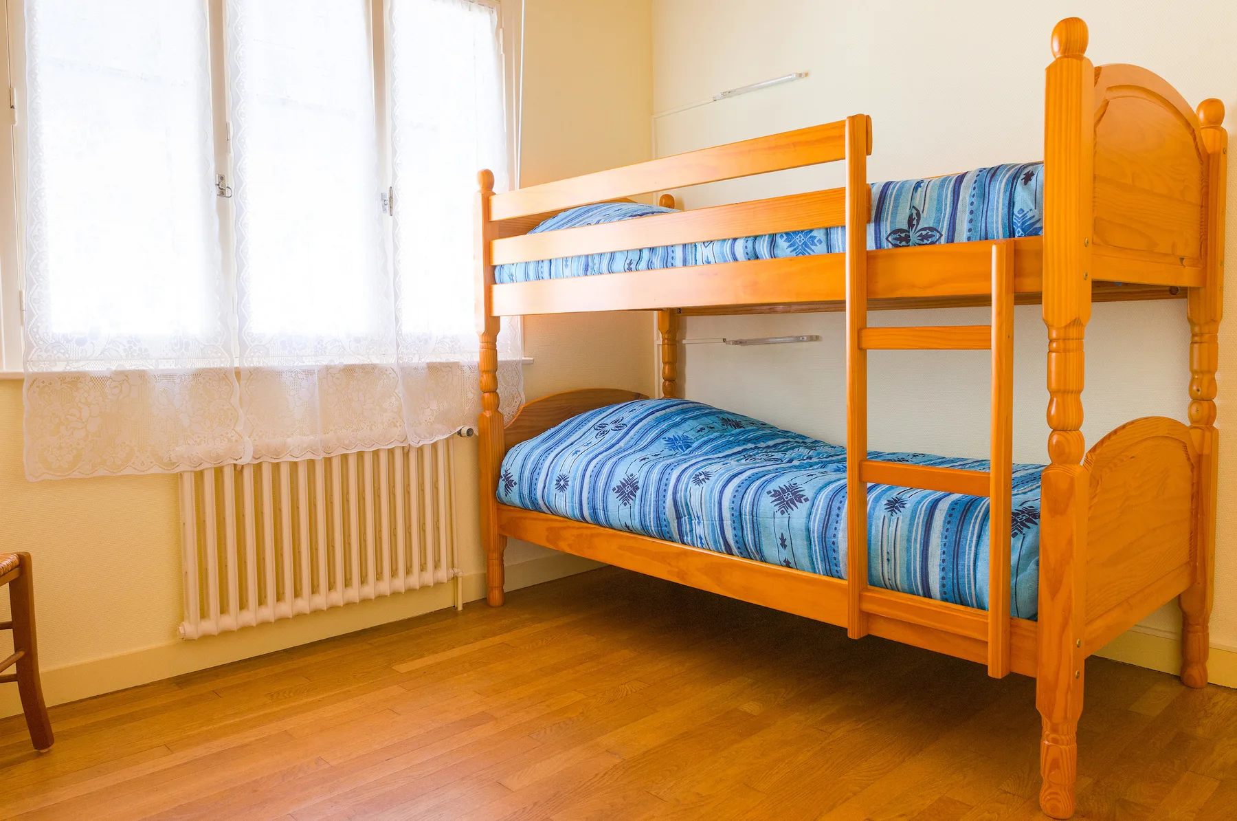 A bedroom with a wooden bunk bed and blue patterned bedding.