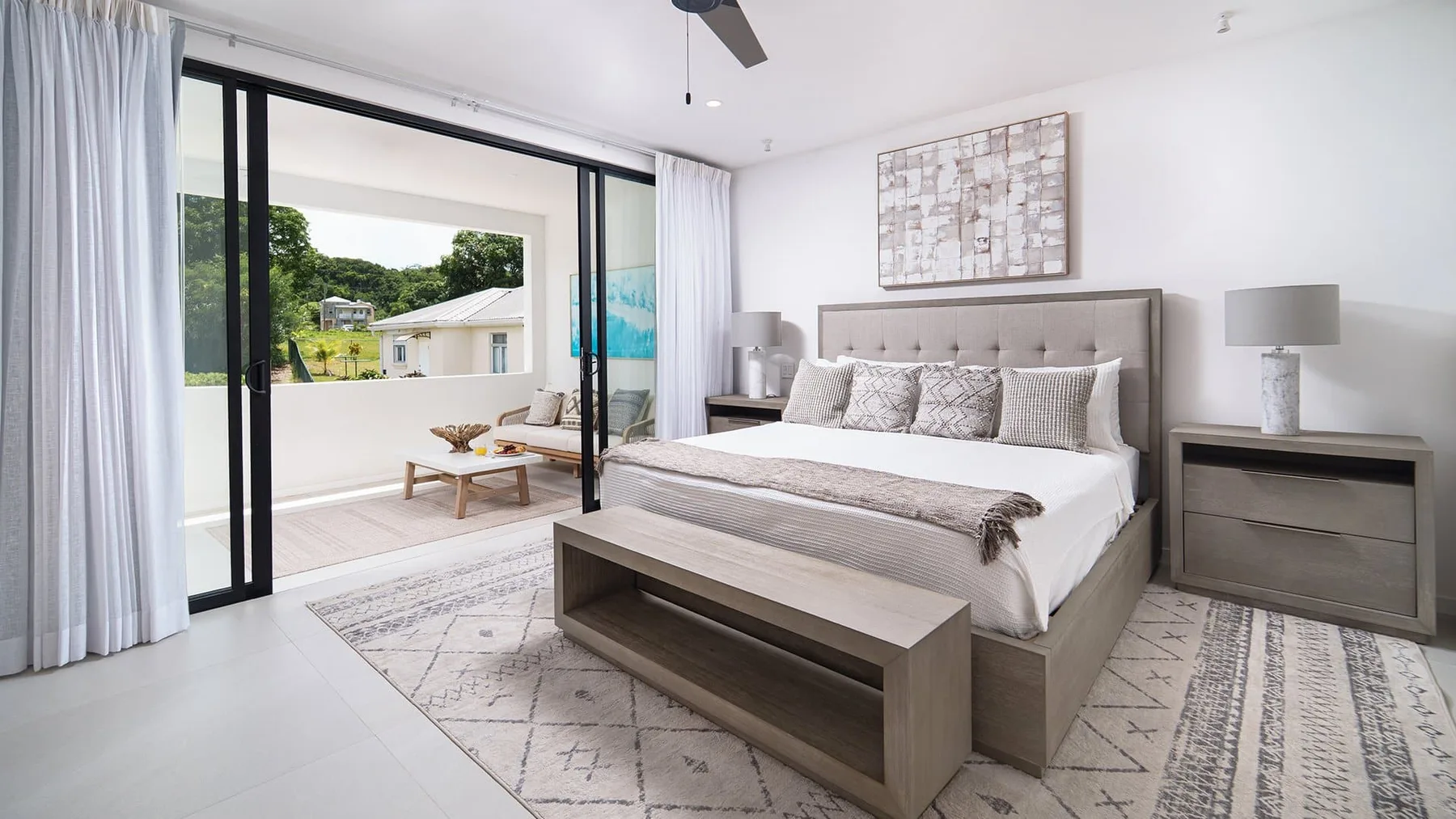Un dormitorio luminoso con una cama grande y puertas corredizas de vidrio que dan a un balcón.
