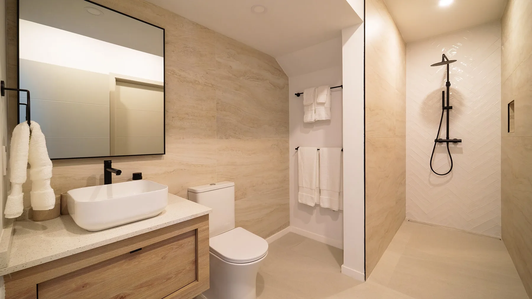 Un baño con un lavabo amplio, espejo de pared, inodoro y zona de ducha abierta.