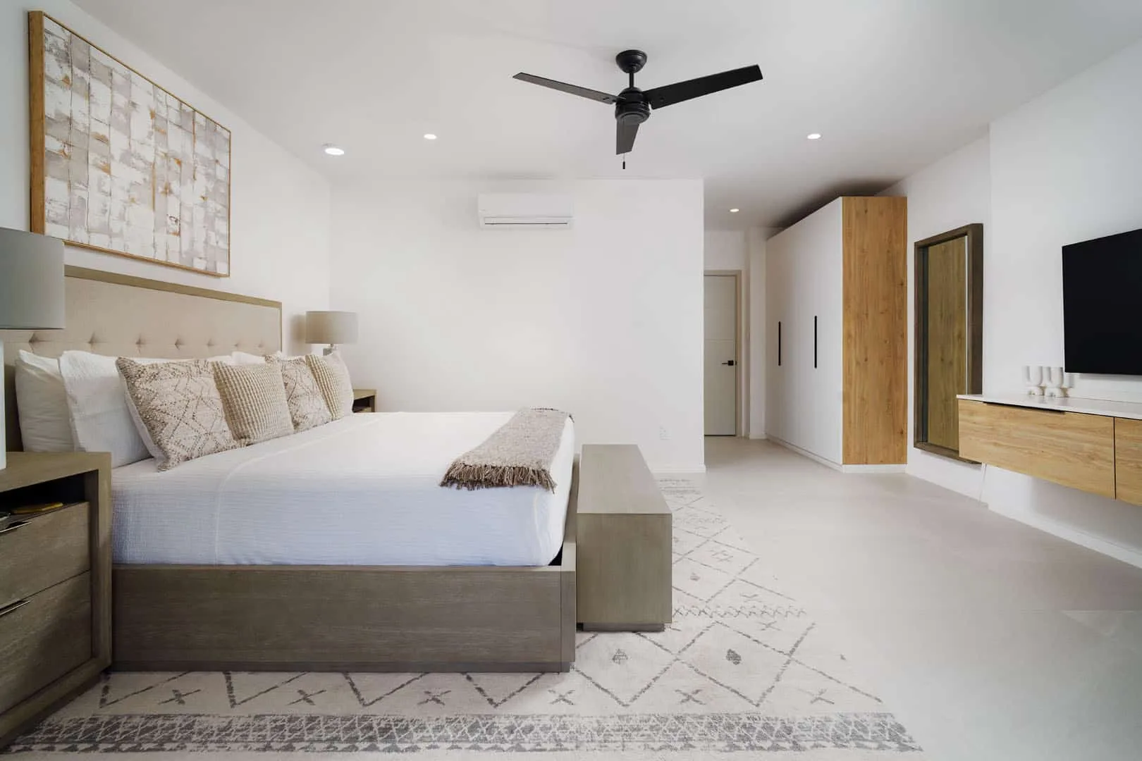 Un dormitorio luminoso con cama, ventilador de techo y armarios empotrados.
