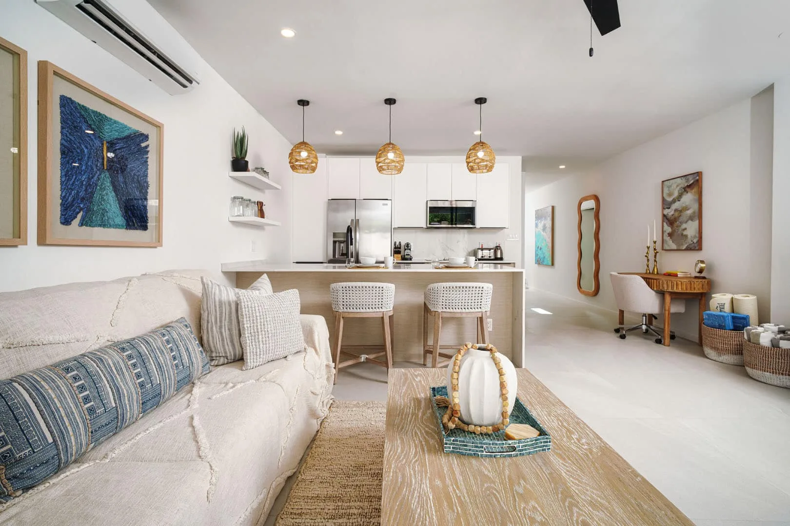 Una sala luminosa se abre a una cocina, con un sofá y una barra de desayuno.