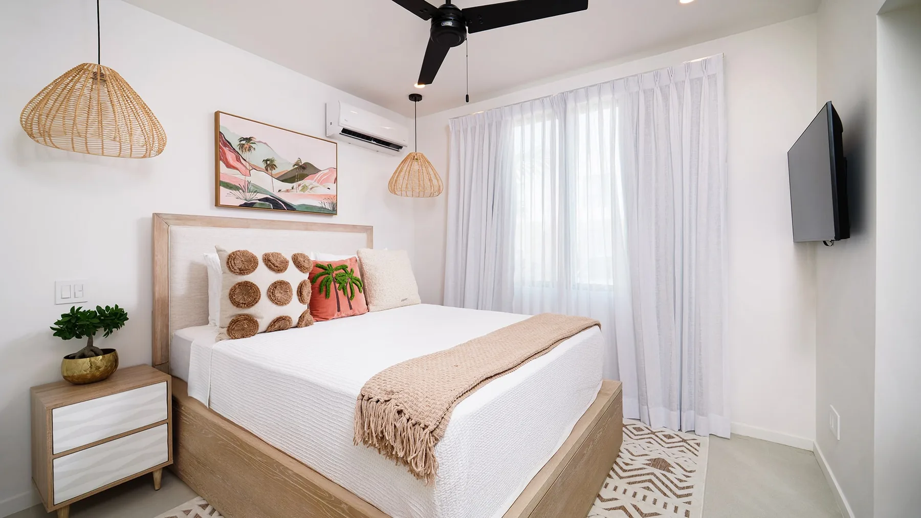 Un dormitorio luminoso con una cama tendida y cortinas translúcidas.