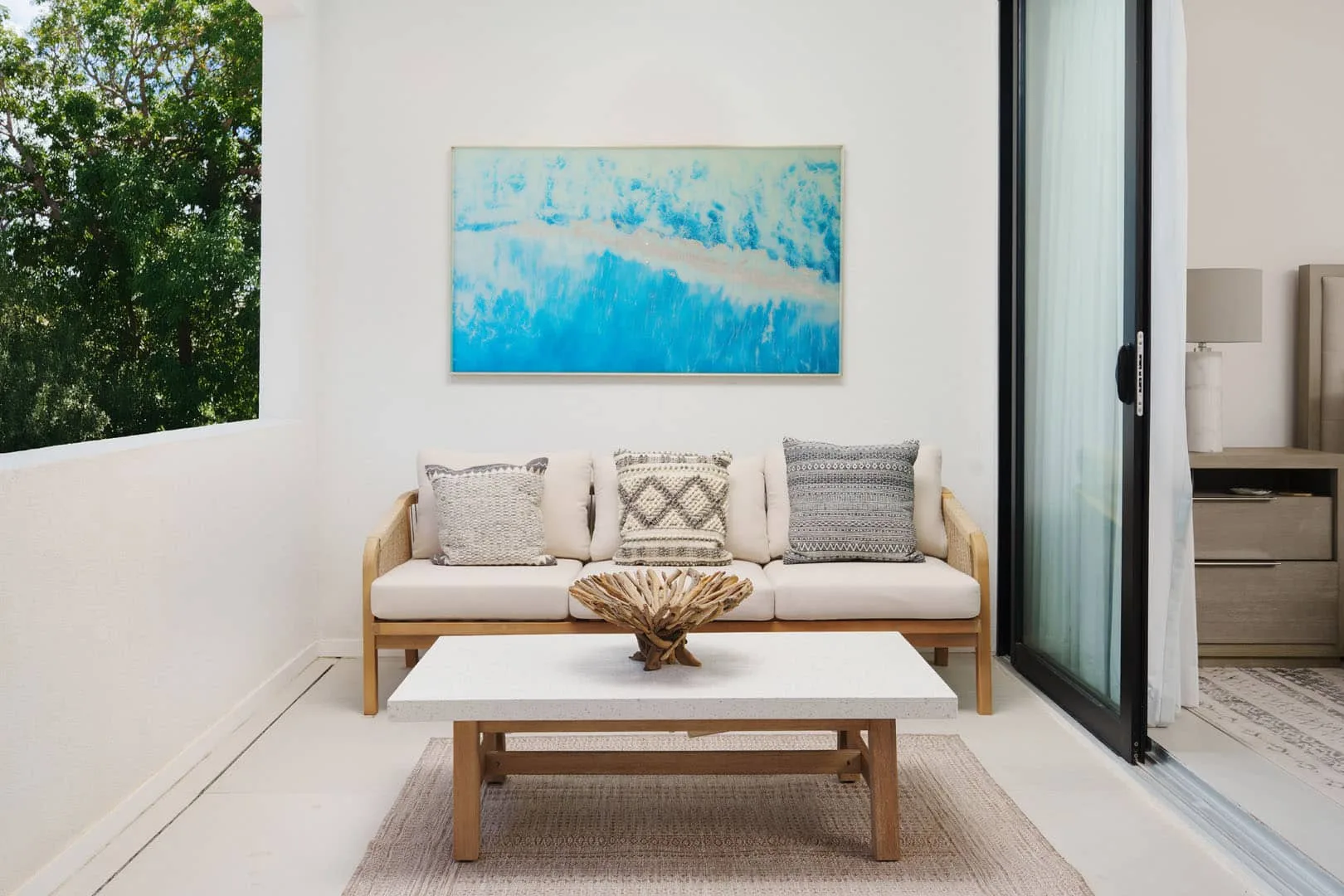 Una luminosa sala de estar con sofá, mesa de centro y arte azul en la pared.