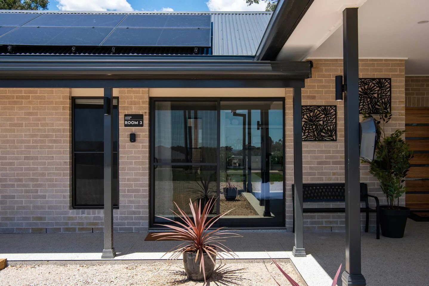 A brick building entrance with large glass doors beneath a covered walkway.