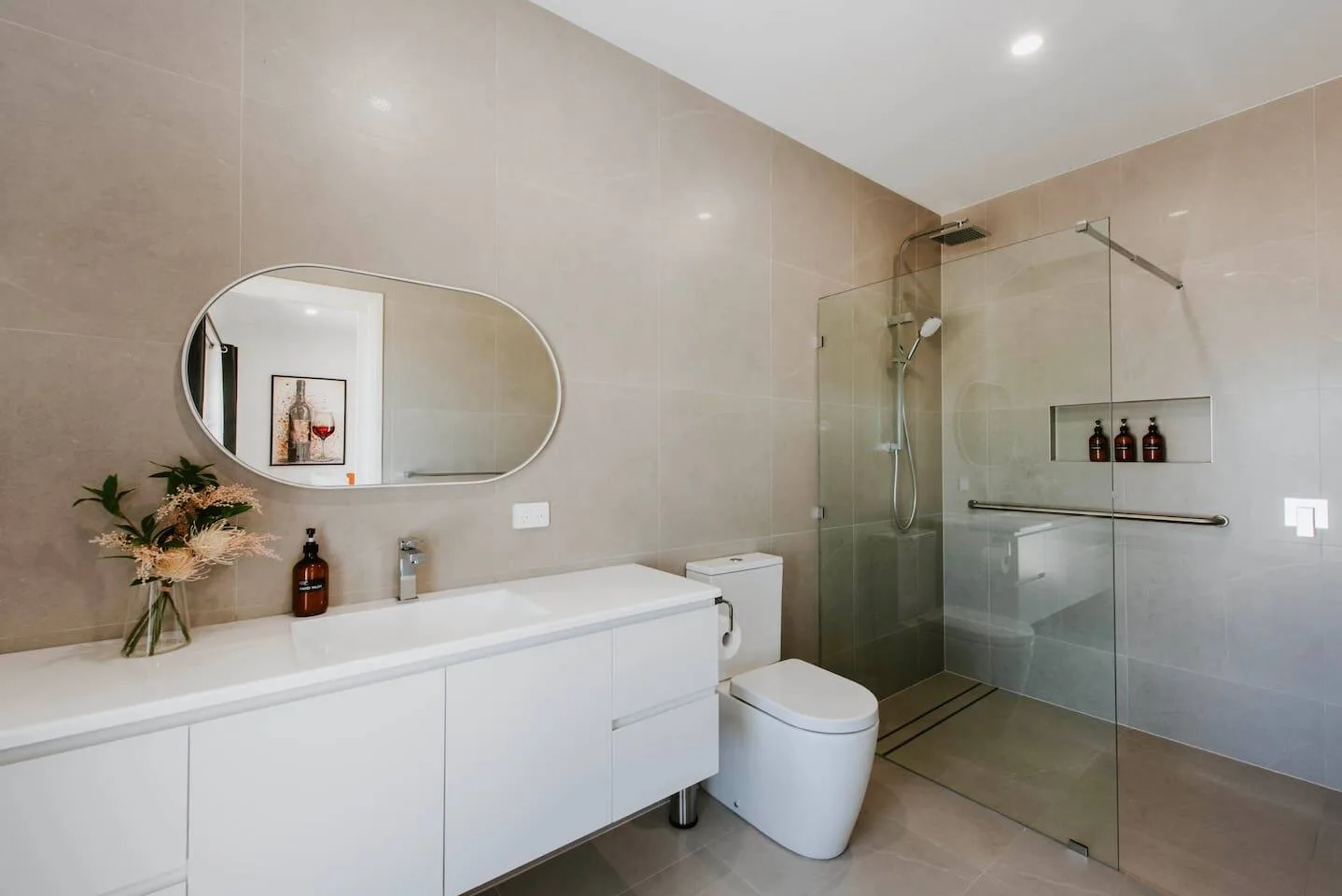 Un baño moderno con mueble de lavabo, inodoro y ducha con mampara de vidrio.