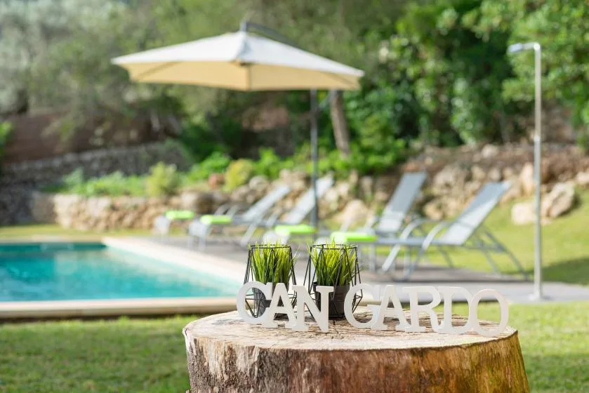 A swimming pool and lounge chairs sit behind a wooden stump with decorative lettering.