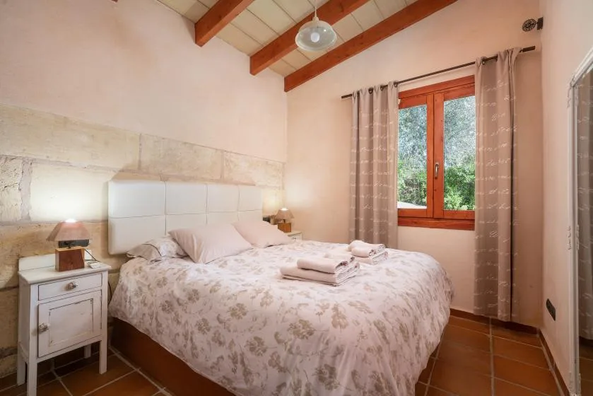 A bedroom with a double bed, bedside tables, and a window with curtains.