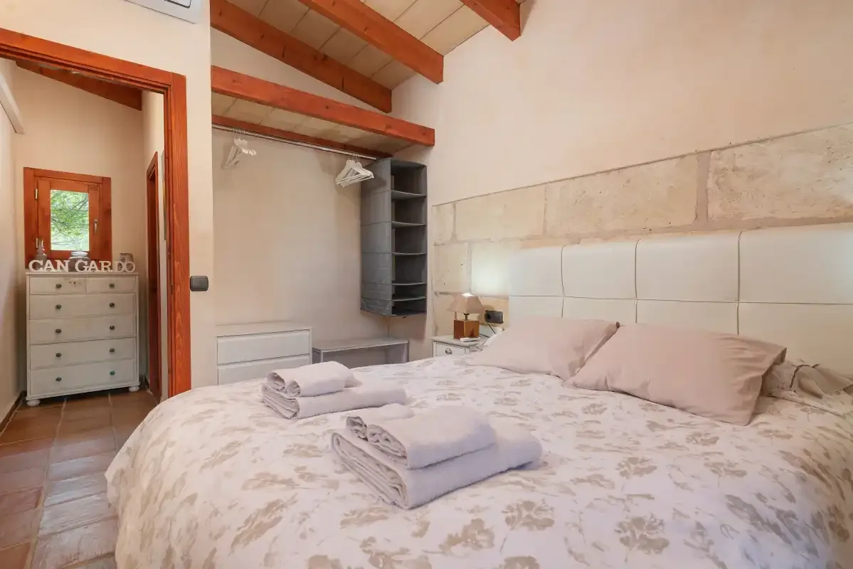 A bedroom with a bed dressed in floral bedding and folded towels.