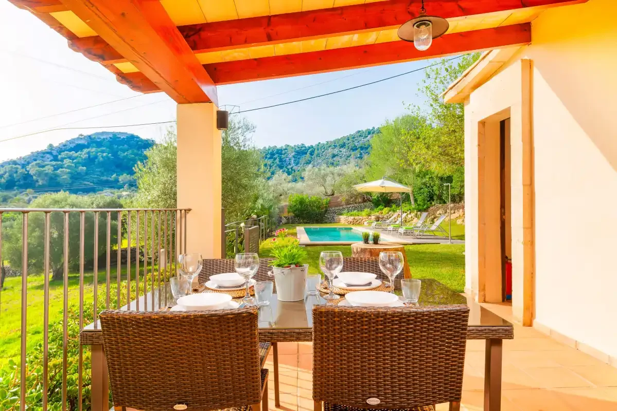 A covered outdoor dining terrace overlooks a garden and swimming pool.