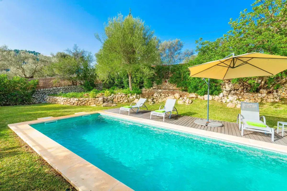 An outdoor swimming pool beside a wooden deck and garden seating.