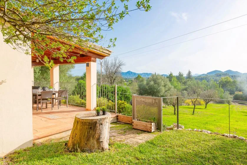 A covered outdoor patio opens onto a green lawn and distant hills.