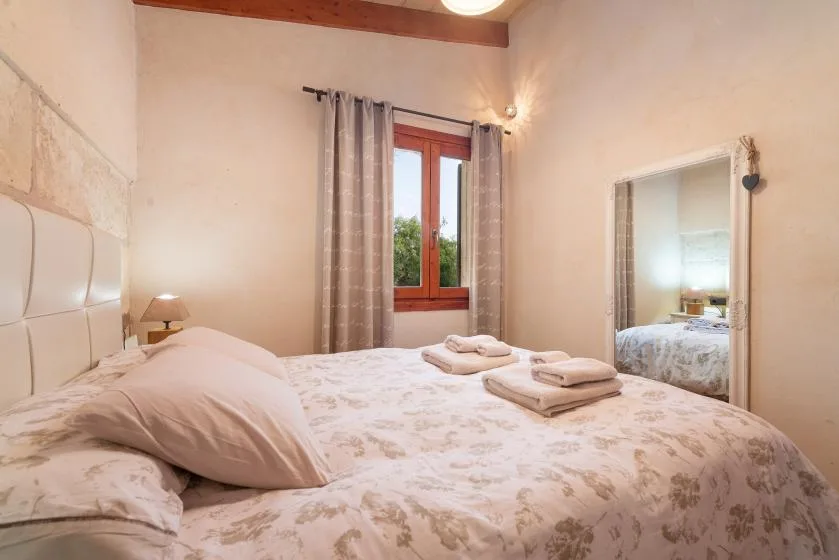A bedroom with a large bed and a curtained window.