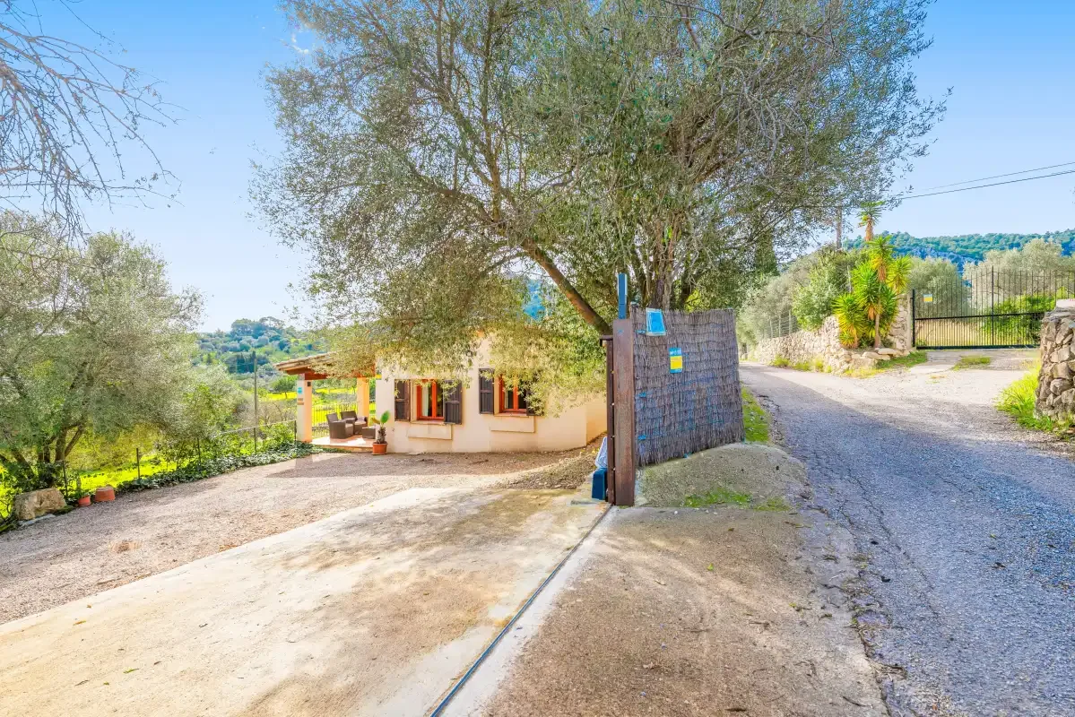A small building stands beside a driveway and gated entrance.