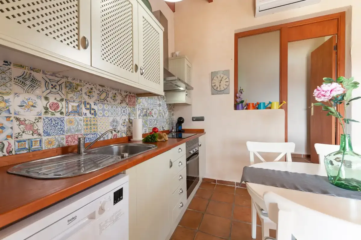 A tiled kitchen with a countertop and a small dining table.