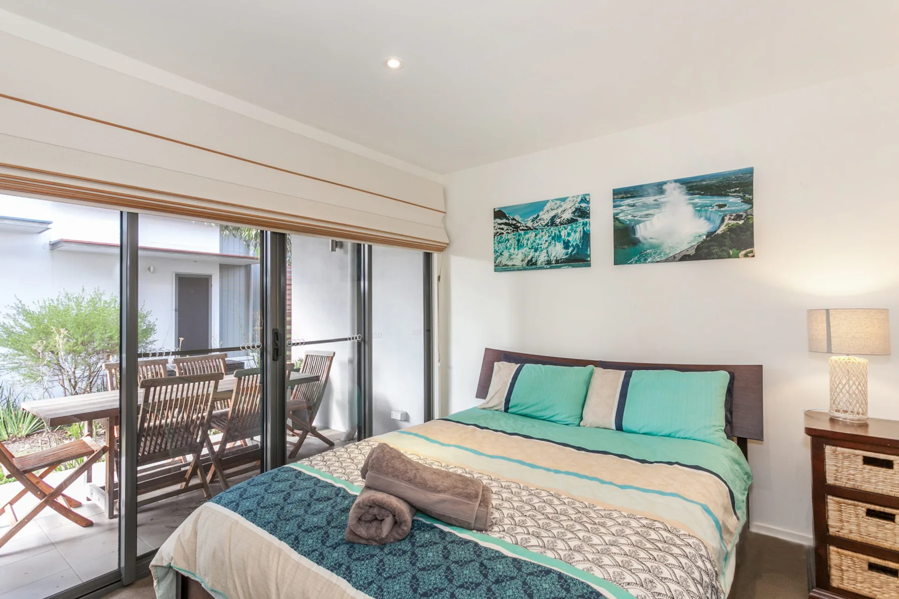 A bedroom with a bed beside sliding glass doors opening onto a furnished patio.