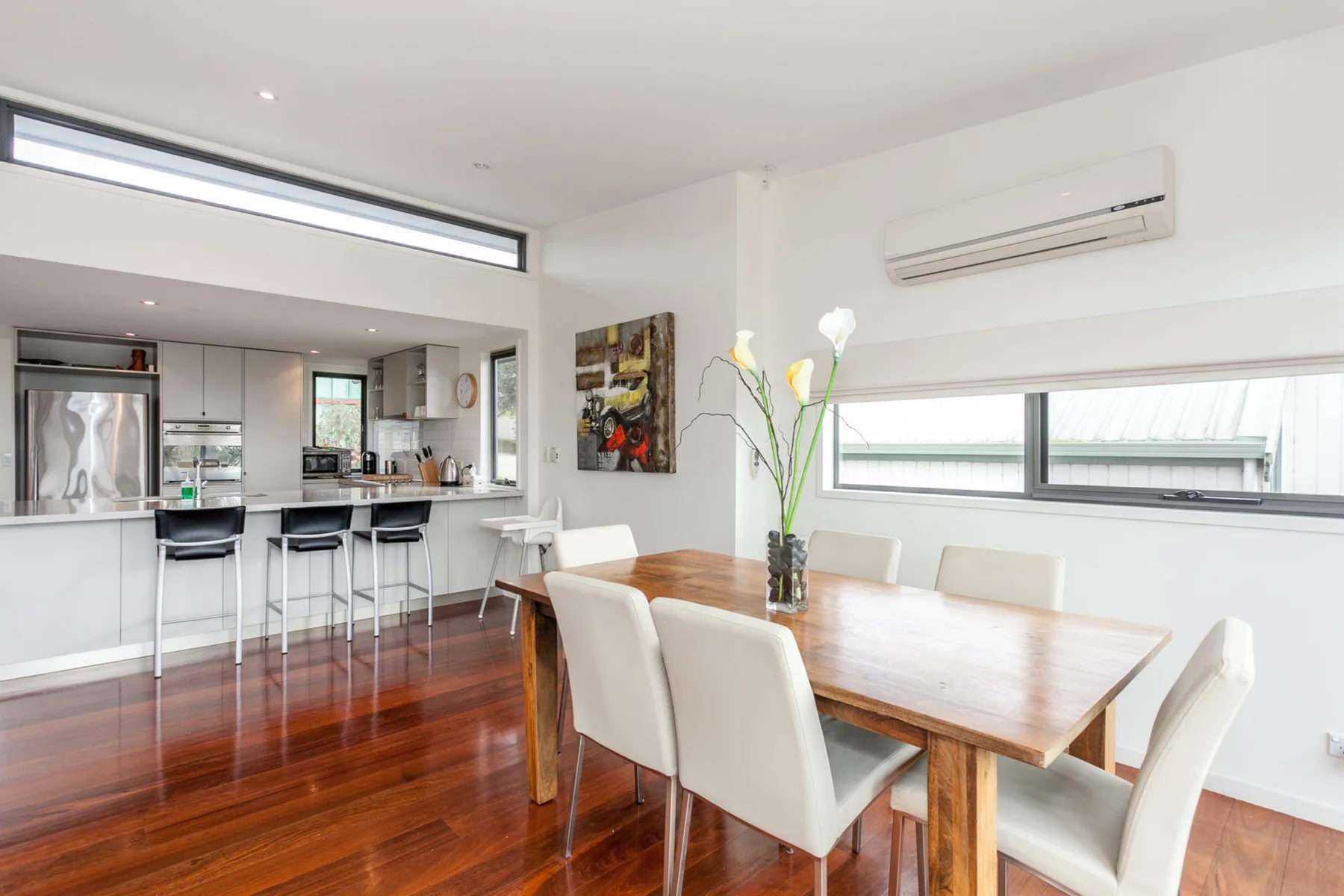 A bright dining area with a wooden table beside an open kitchen.