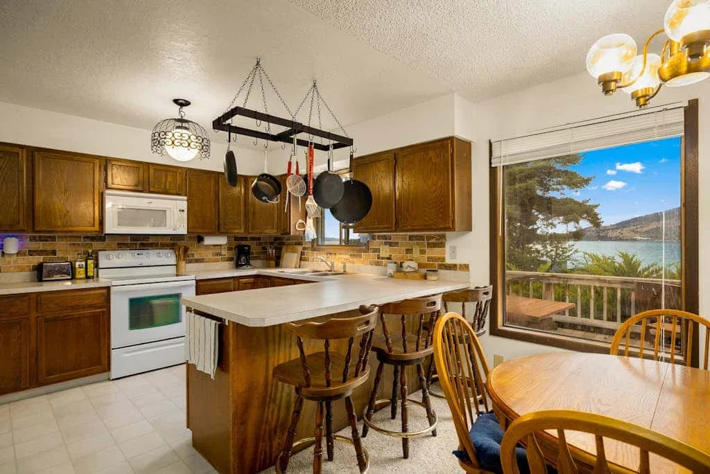 A kitchen and dining area with wooden cabinets and a large window overlooking the water.
