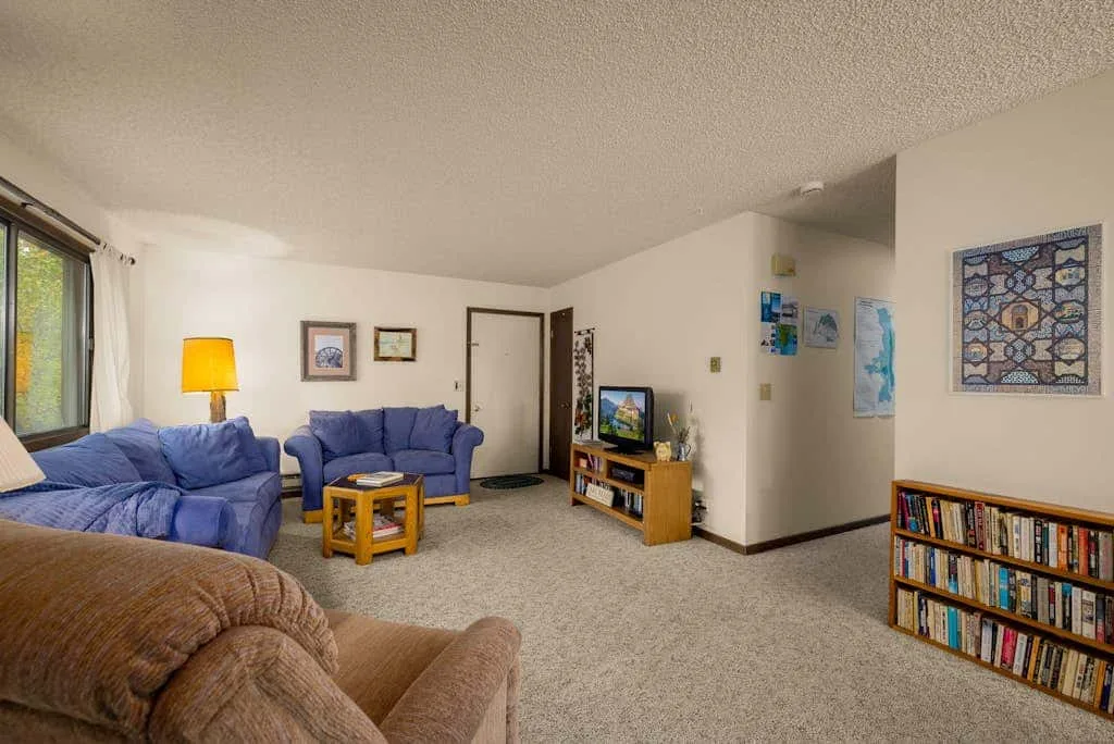 A living room with seating, a television, and a bookcase.