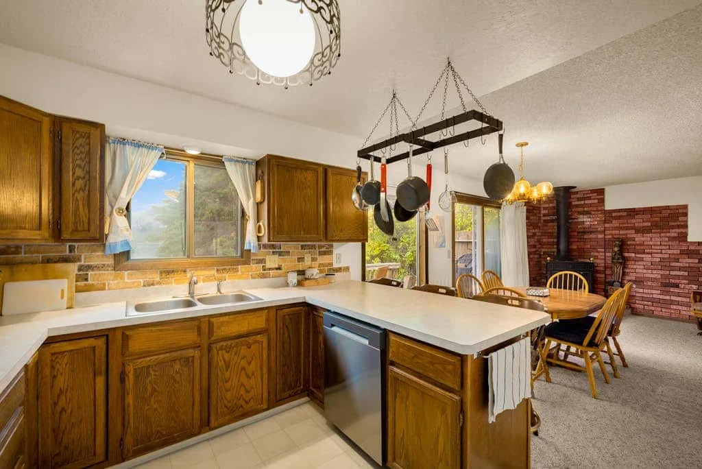 A kitchen with wooden cabinets and a large central island opens onto a dining area.
