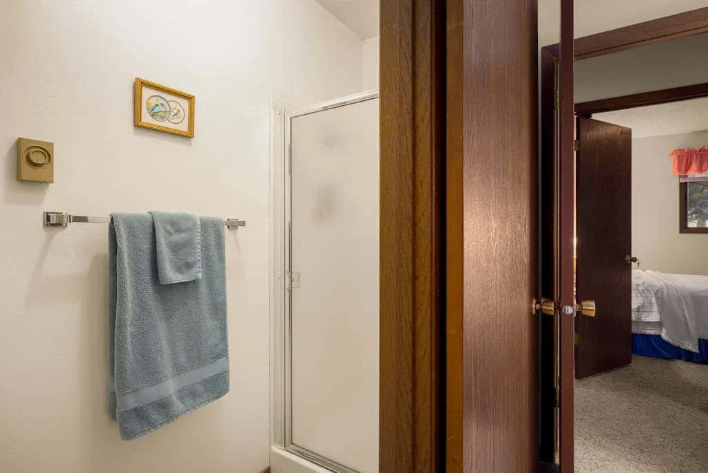 A bathroom with a towel hanging beside a shower.