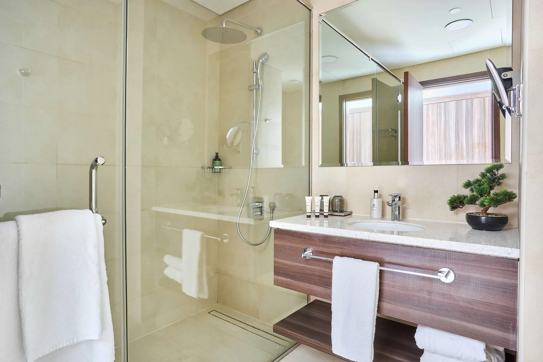 A bathroom with a glass shower and a vanity topped with a sink.