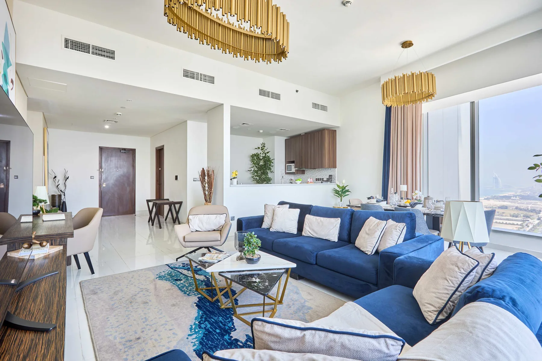 A bright living room with blue seating, a coffee table, and large windows.