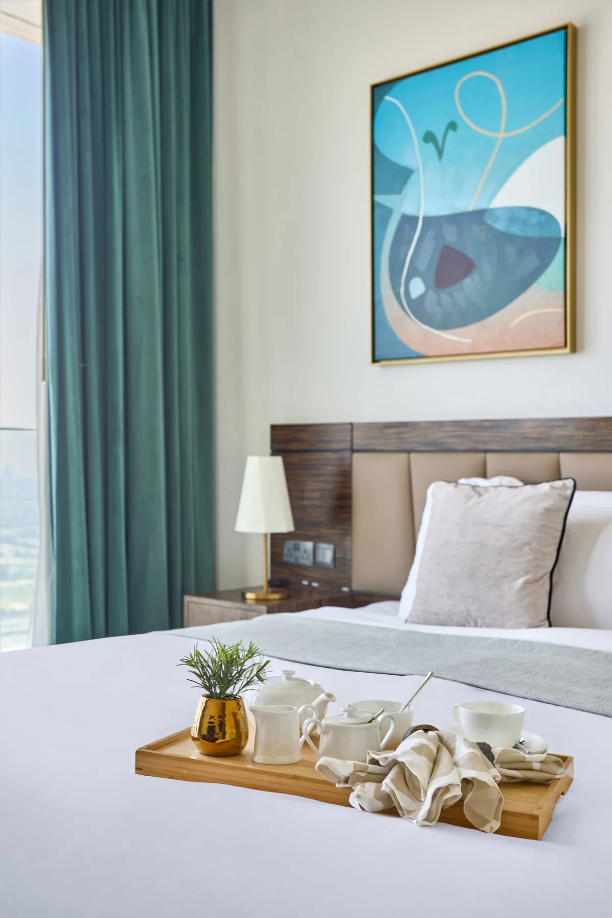 A bedroom with a neatly made bed and a wooden breakfast tray.
