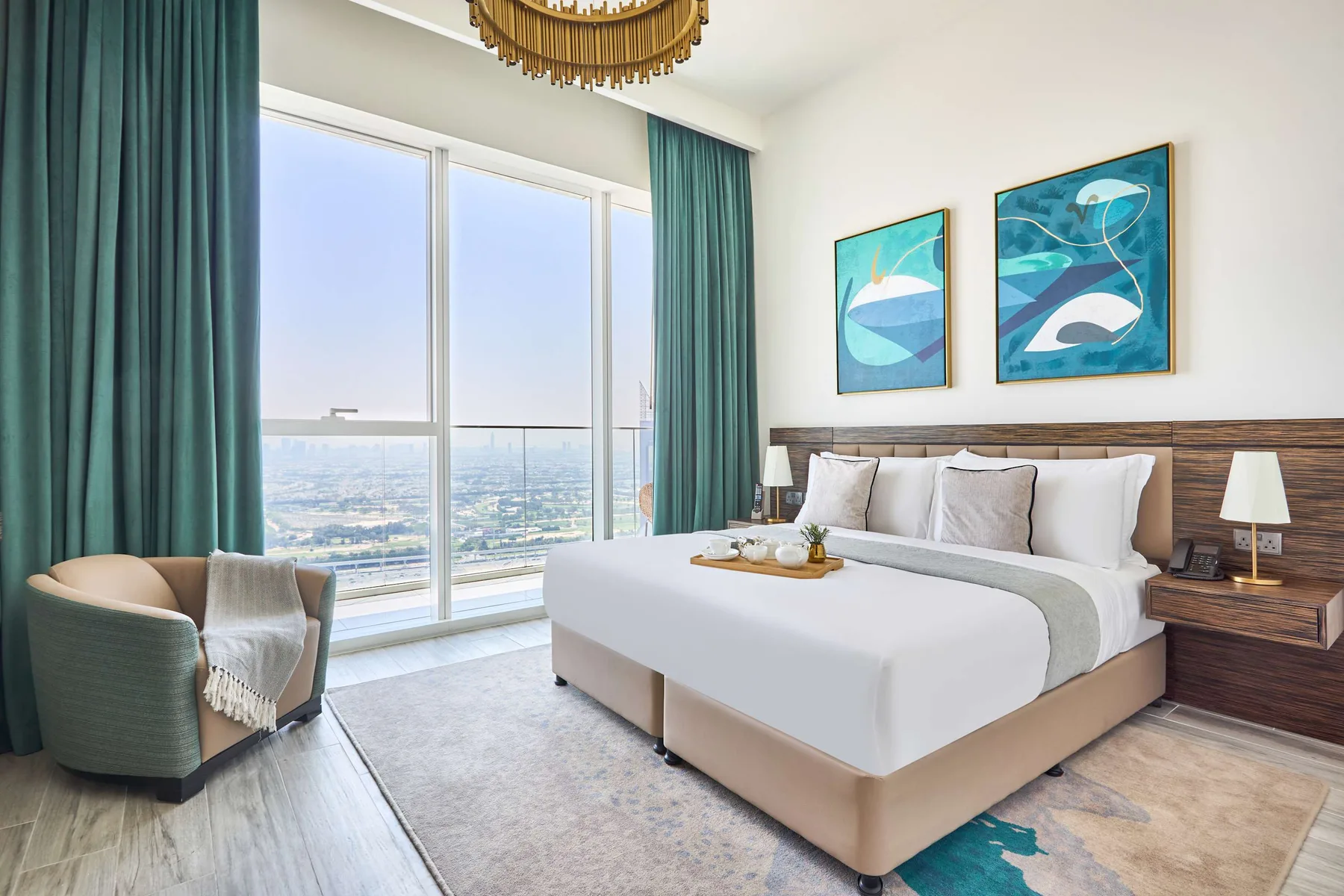 A bedroom with a neatly made bed, teal curtains, and large windows.