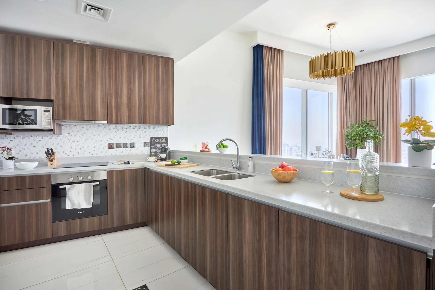 A modern kitchen with dark wood cabinets, a long counter, and large windows.
