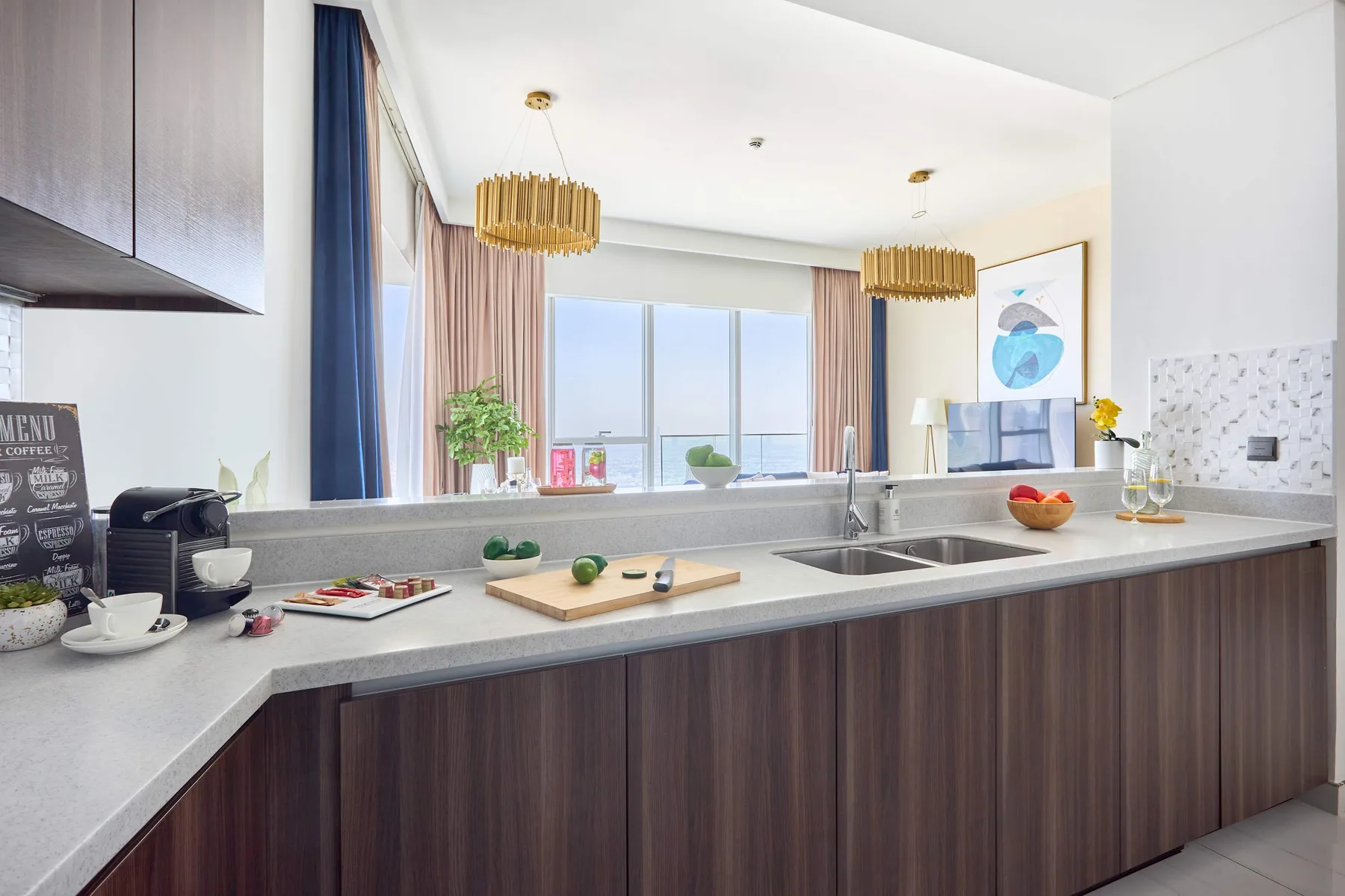 A modern kitchen with a long counter facing large windows.