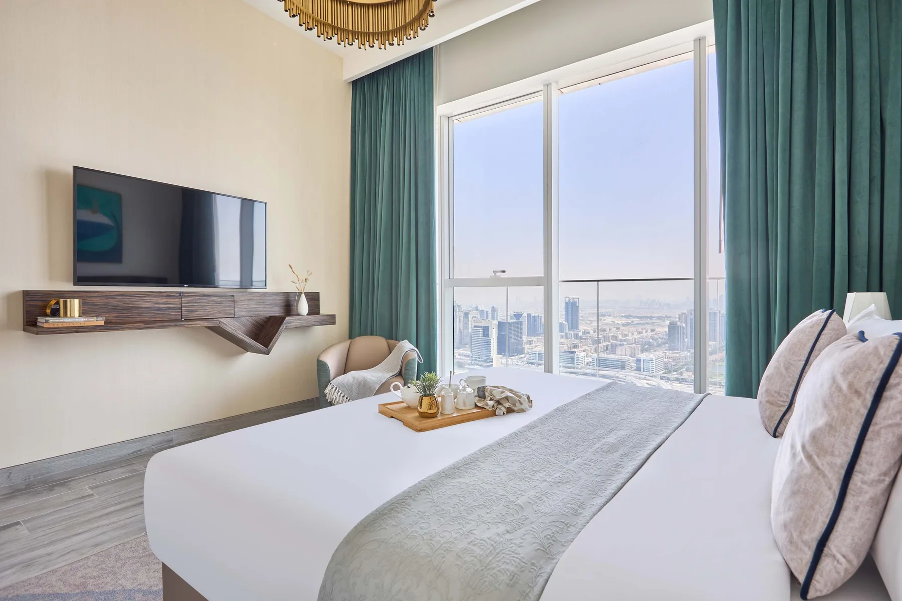 A bedroom with a neatly made bed and floor-to-ceiling windows overlooking the city.