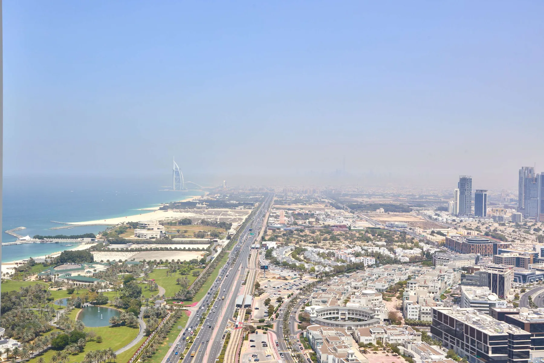 Aerial cityscape overlooking a coastal shoreline, roads, and clusters of buildings.
