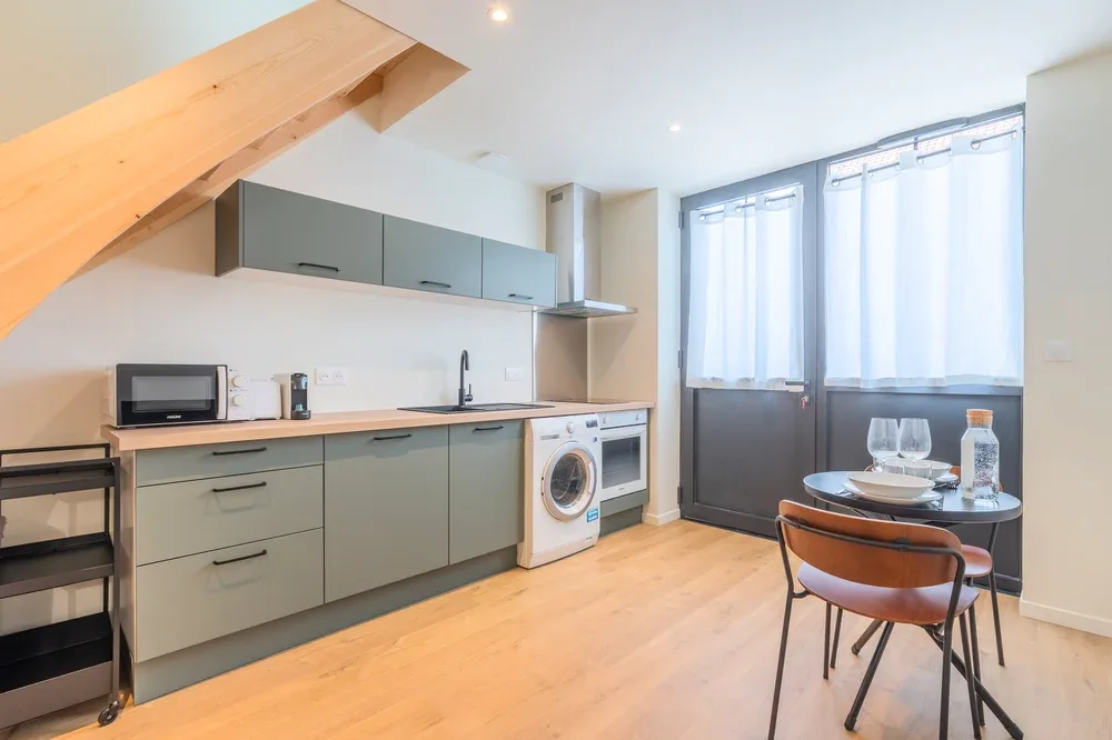 A bright kitchen and dining area with a counter, cabinets, and a small table.