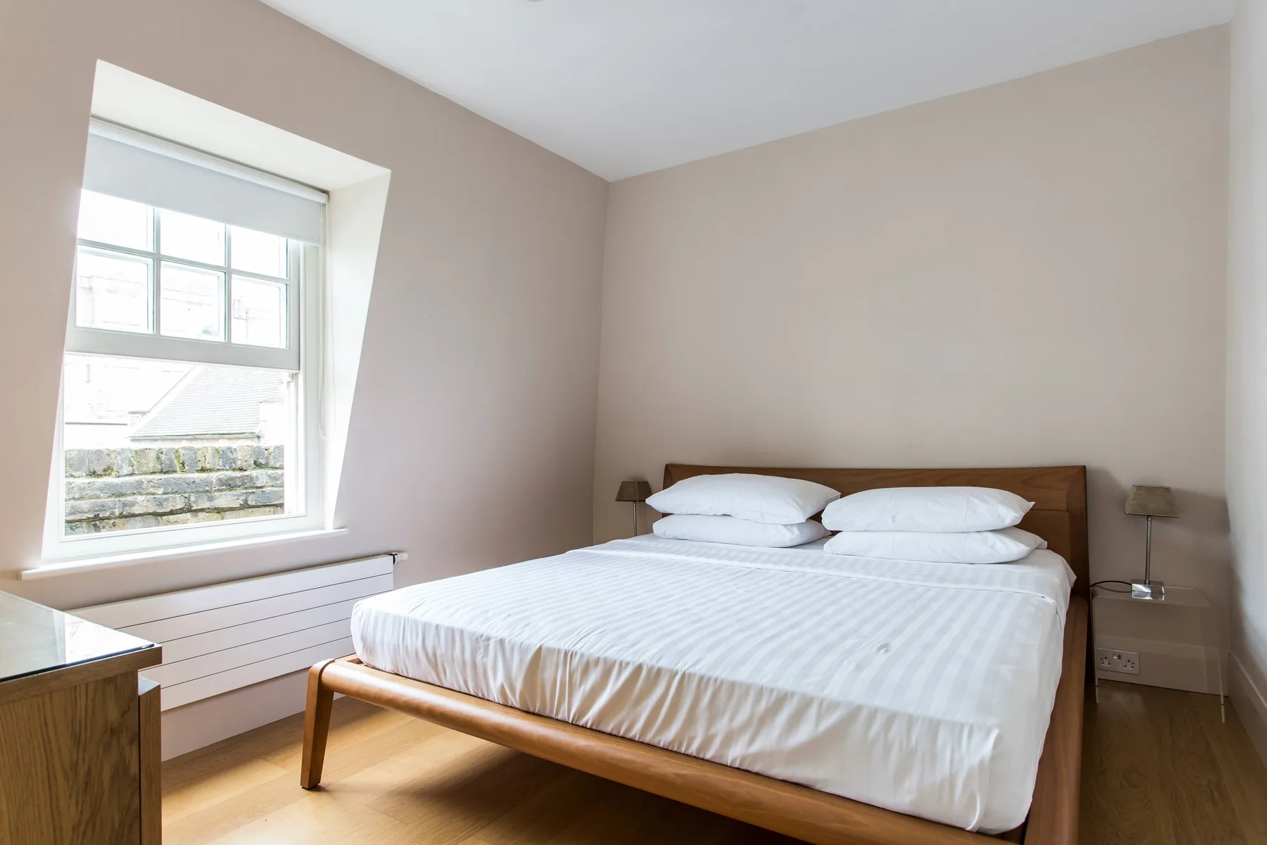 Un dormitorio con una cama, mesas de noche y una ventana.