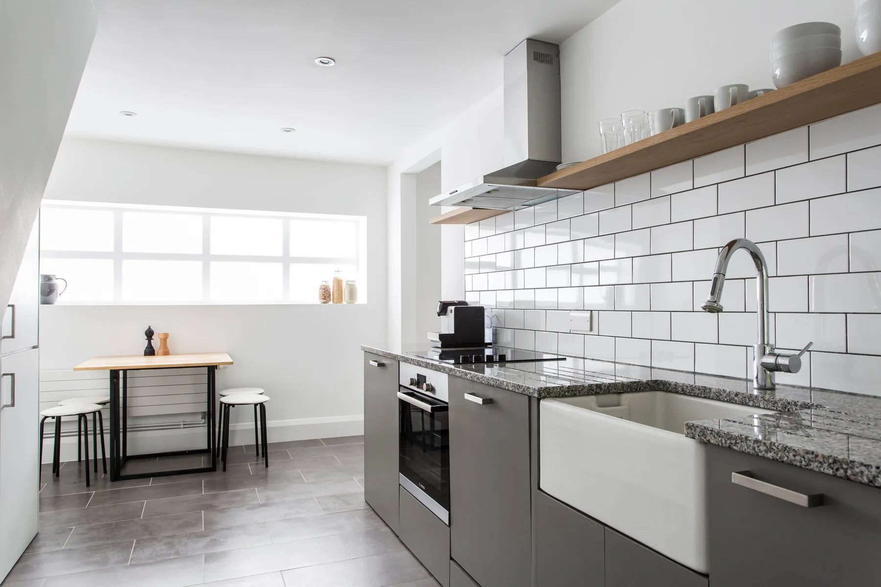 A bright kitchen with a long counter and a small dining table by the window.