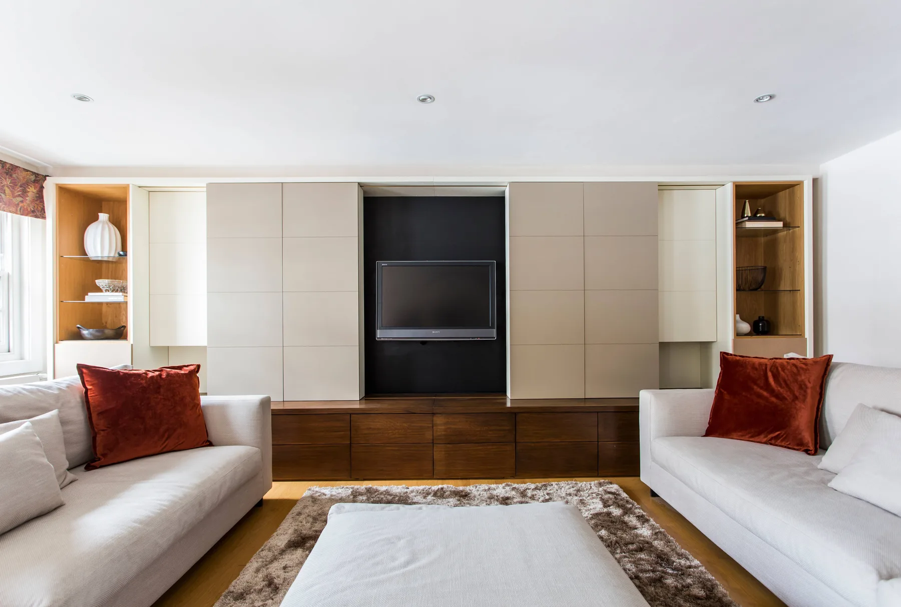 A bright living room with two seating areas facing a television and a low table.