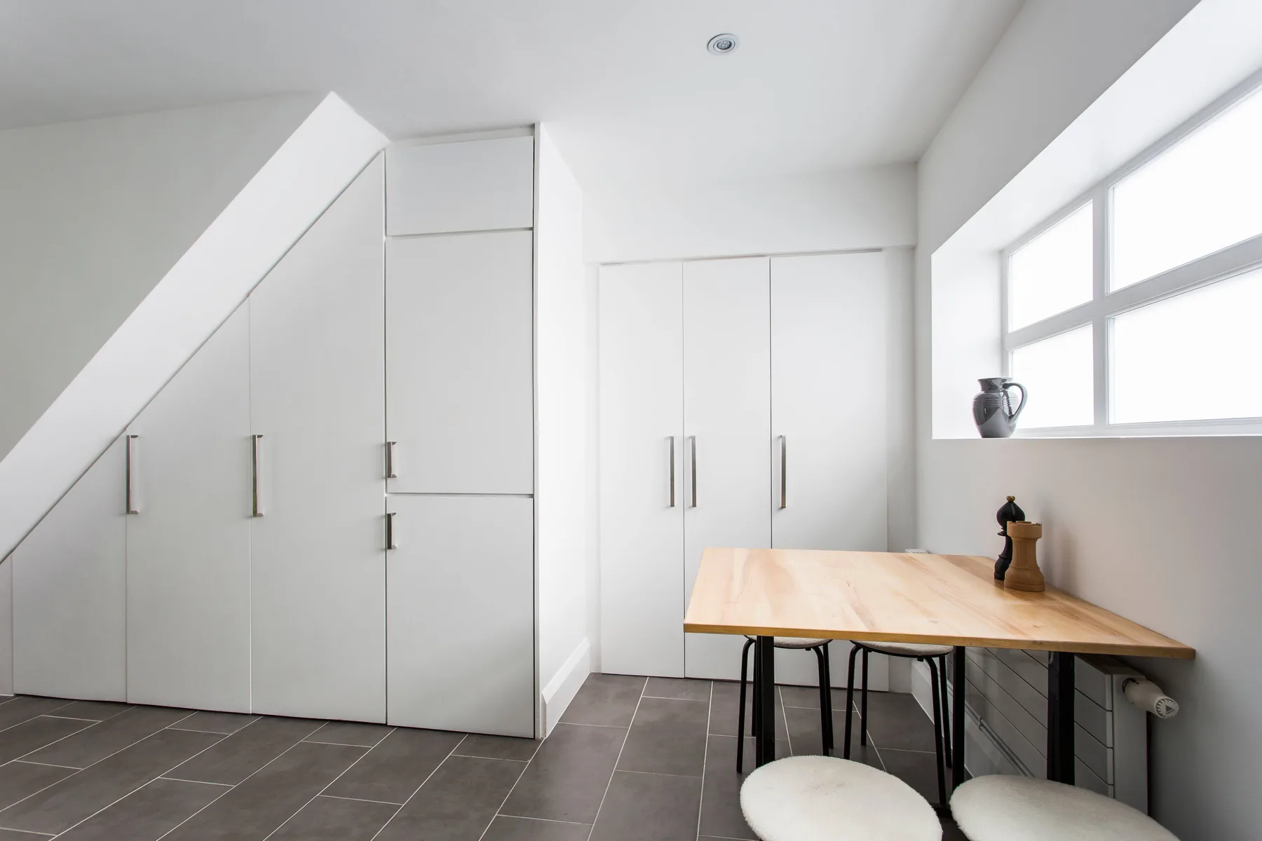 A bright room with built-in white cabinets and a wooden table beneath a window.