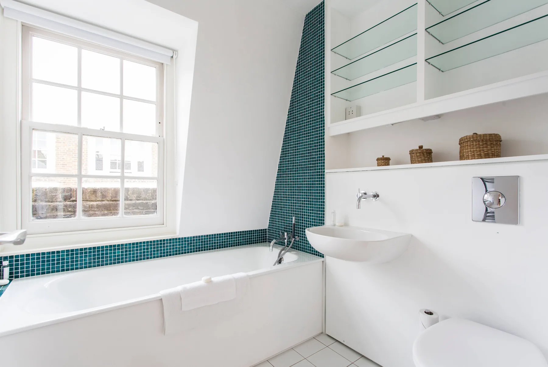 Un baño luminoso con bañera, lavabo y una ventana grande.