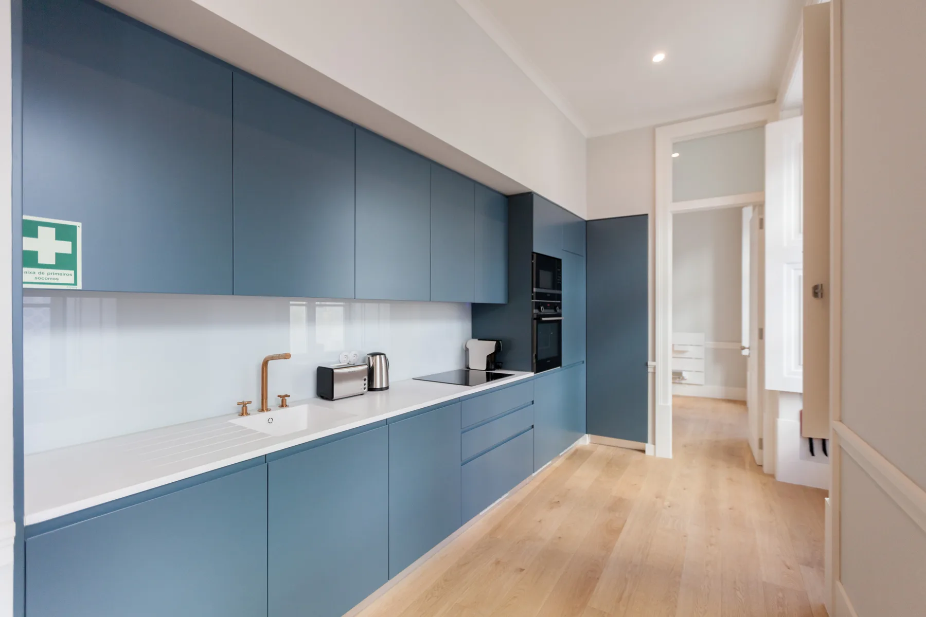 Una cocina moderna con gabinetes azules y una encimera blanca larga.