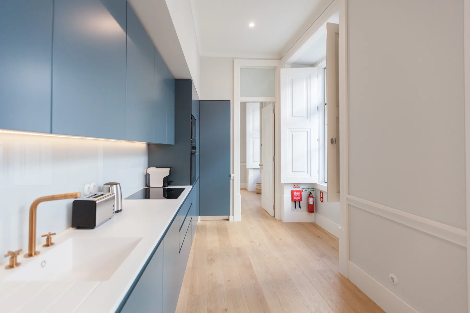 Una cocina moderna con armarios azules y una encimera blanca alargada.