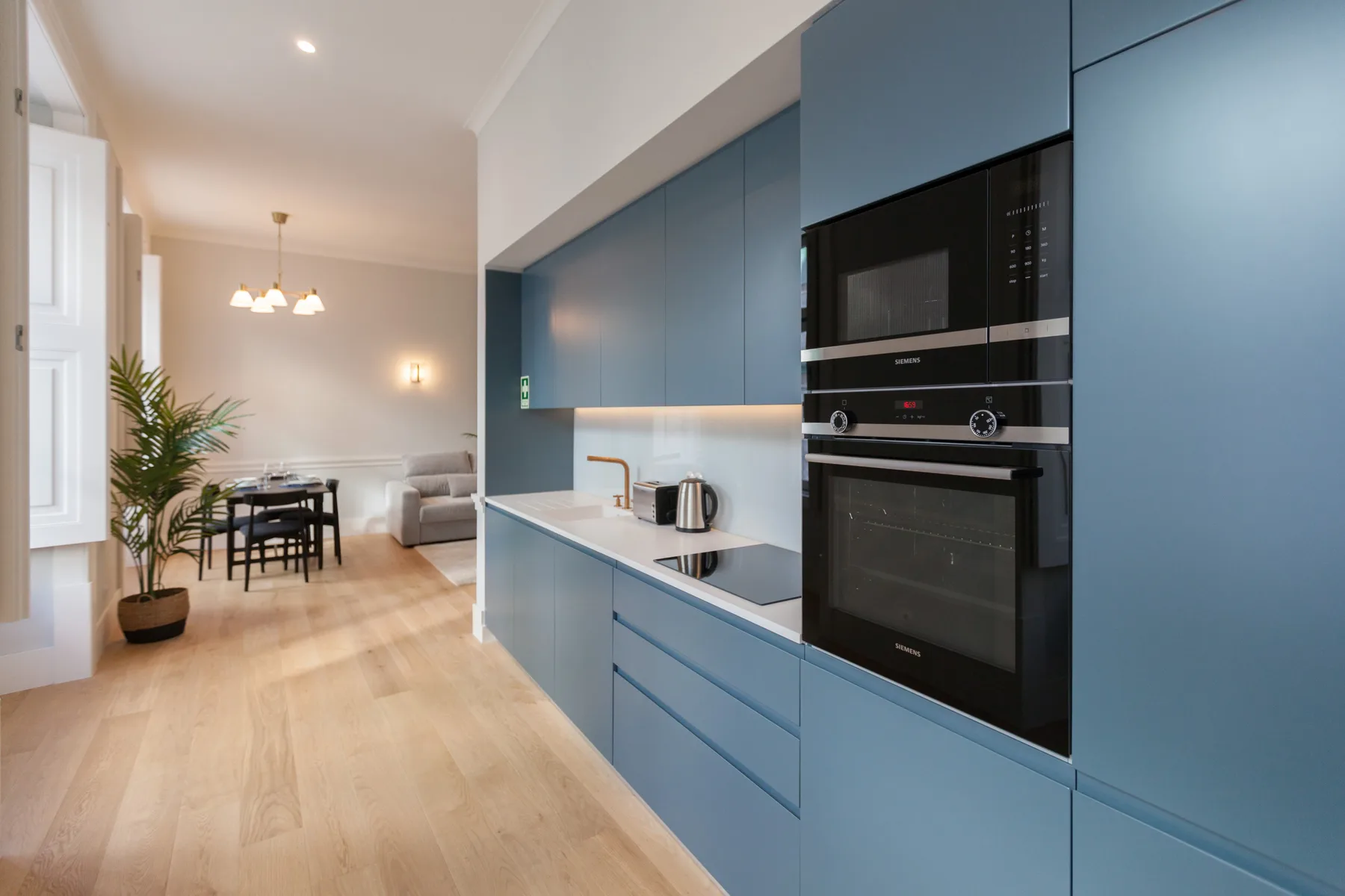 Una cocina moderna con gabinetes azules se abre a una zona de comedor y estar.