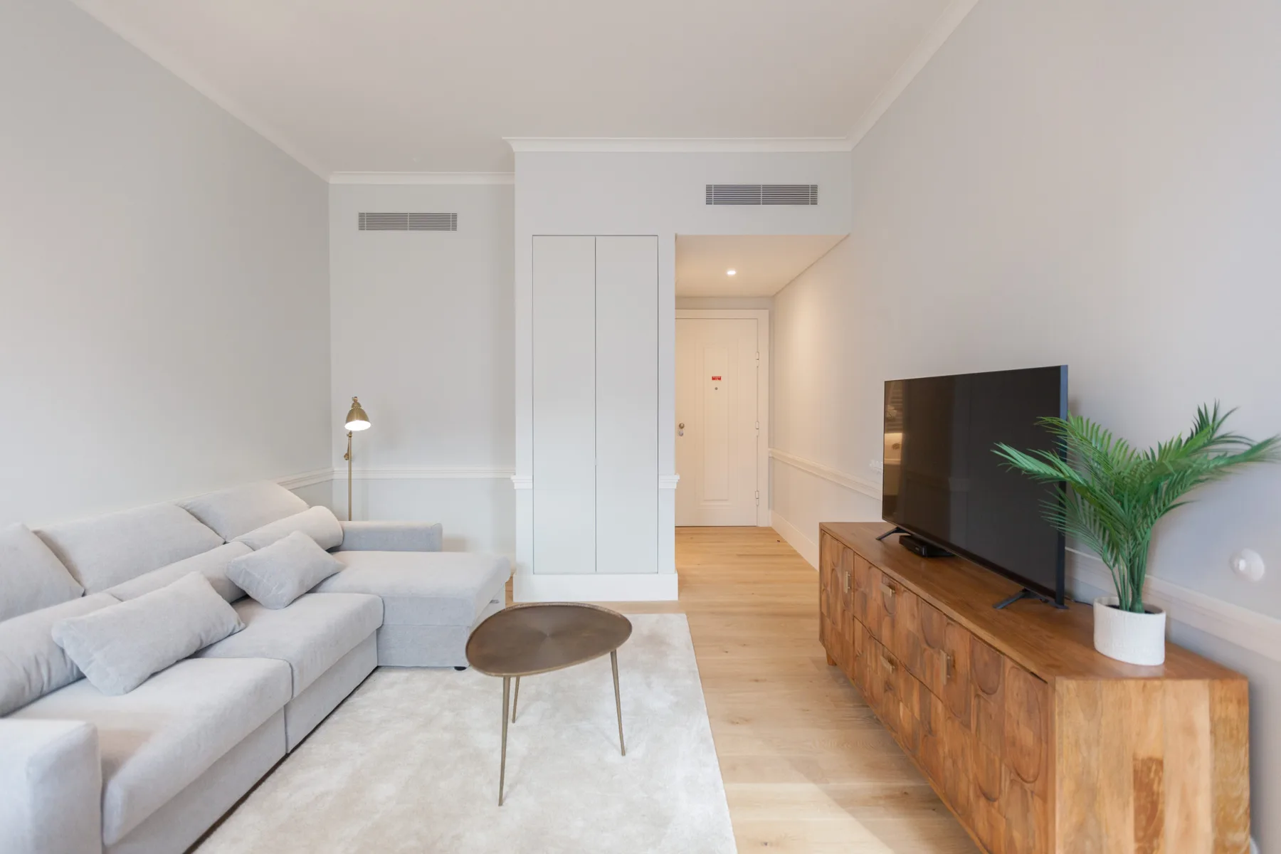 Una sala luminosa con asientos, un televisor y un mueble de madera.
