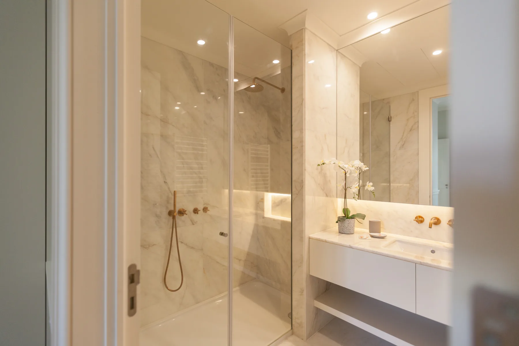 Un baño luminoso con ducha acristalada y lavabo.